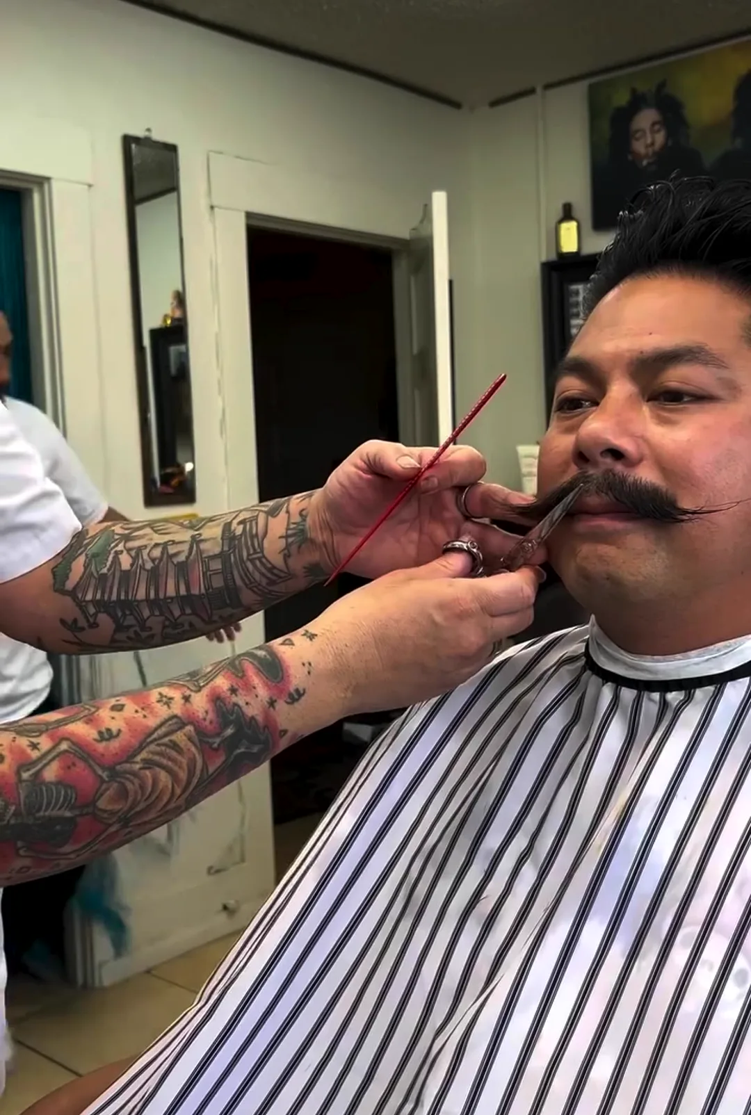 Chavo shaping a handlebar mustache with a straight razor